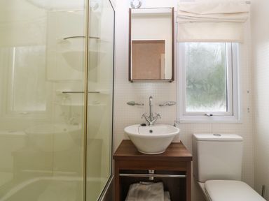 A bathroom with a shower enclosure sink with faucet mirror toilet and frosted window at Gwel Eryri in Penmynydd near Llanfairpwllgwyngyll