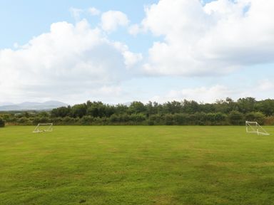 A grass field with two small soccer goals and trees in the background at Gwel Eryri in Penmynydd near Llanfairpwllgwyngyll