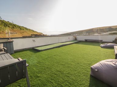 A rooftop area with artificial grass a putting green two bean bag chairs and seating at 12 Beachdown in Challaborough