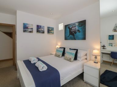 A bedroom with a double bed pillows bedside tables lamps and a desk with a chair at 12 Beachdown in Challaborough