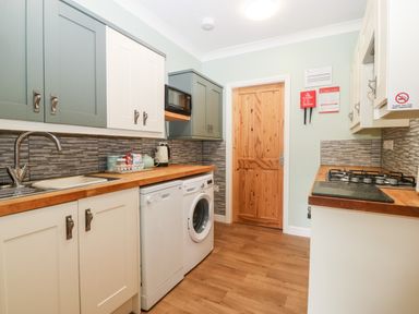 A kitchen with wooden countertops washing machine gas stove and wooden door at Coed y Glyn Bach Equestrian Penygroes