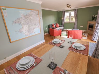 A dining table set with plates and wine glasses in a living room with sofas and a map on the wall at The Annexe Meadow Croft in Haverfordwest