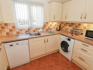 A kitchen with a dishwasher washing machine toaster microwave and sink at The Annexe Meadow Croft in Haverfordwest