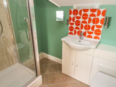 A bathroom with a shower enclosure sink with red and white tiled backsplash and a wall-mounted mirror at The Annexe Meadow Croft in Haverfordwest