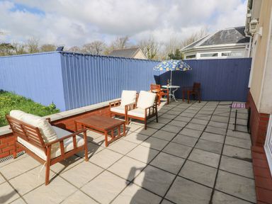 A patio with wooden seating and a table with an umbrella at The Annexe Meadow Croft in Haverfordwest