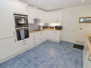 A kitchen with blue tiled floor white cabinets wooden countertops and built in double oven at 3 Strawberry Close Little Haven near Broad Haven