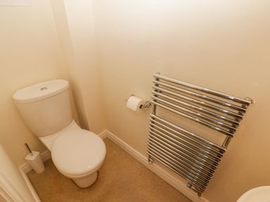 A toilet with a toilet brush holder and a wall-mounted chrome towel radiator at 3 Strawberry Close in Little Haven near Broad Haven
