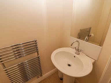 A bathroom sink with a faucet a wall-mounted towel radiator and a mirror at 3 Strawberry Close Little Haven near Broad Haven