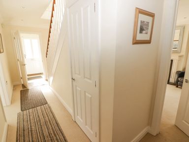 A hallway with striped rugs a staircase white doors and a framed picture at 3 Strawberry Close in Little Haven near Broad Haven