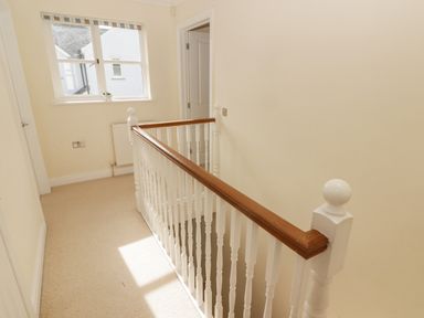 A hallway with a window radiator and staircase with white wooden railing at 3 Strawberry Close Little Haven near Broad Haven