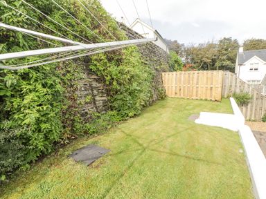 A small grass garden with a rotary clothesline and wooden fence at 3 Strawberry Close in Little Haven near Broad Haven