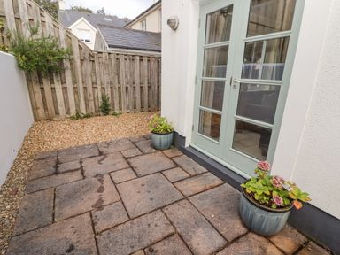 A small patio with two plant pots and glass doors at 3 Strawberry Close in Little Haven near Broad Haven