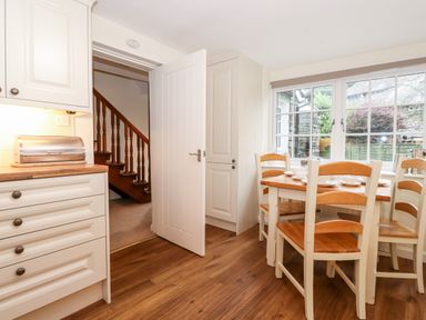 A kitchen dining area with wooden floor chairs and table near large windows at Holly Cottage in Grasmere