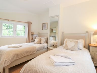 A bedroom with two single beds bedside tables lamps and a window at Holly Cottage in Grasmere