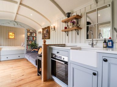 A compact living space with a built-in bed sofa bookshelf kitchen units and sink at Utopia in Metfield near Harleston