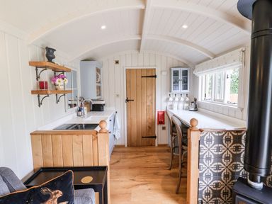 A kitchen with wooden floor wooden door white cabinets a stove and a black wood stove at Utopia Metfield near Harleston