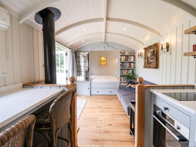An interior with a built-in bed bookshelf sofa kitchen area with oven and dining counter with wicker chairs at Utopia in Metfield near Harleston
