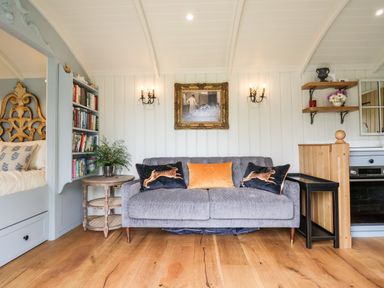 A sitting area with a grey sofa with cushions and a framed painting on the wall at Utopia in Metfield near Harleston