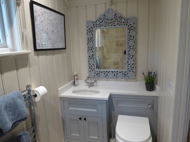 A bathroom with a sink countertop mirror toilet towel rail and framed map on the wall at Utopia Metfield near Harleston