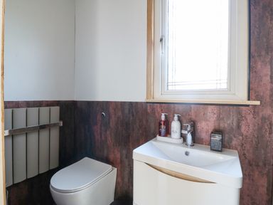 A bathroom with a toilet sink window and soap dispensers at Nyth Y Bioden Magpie's Nest Llanaelhaearn near Trefor