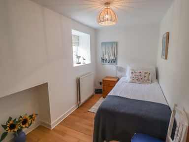 A bedroom with a single bed a nightstand and a chair at Grebe Cottage in Alnmouth