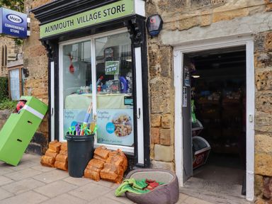 The exterior of Alnmouth Village Store with a display window and an open door showing groceries inside in Alnmouth