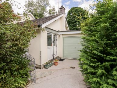 A house exterior with a green garage door plants and a small metal gate at The Lodge in Ambleside
