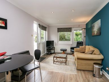 A living room with a beige sofa black armchair coffee table and television at The Lodge in Ambleside