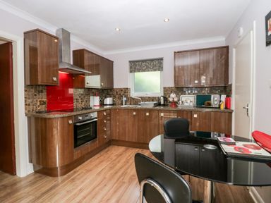 A kitchen with wooden cabinets and a black round table with chairs at The Lodge in Ambleside
