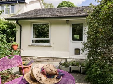 A small outdoor patio area with a purple metal table and chairs and plants near a white building at The Lodge Ambleside