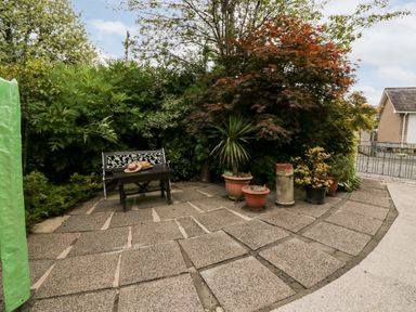 A patio area with a bench and potted plants surrounded by trees at The Lodge in Ambleside