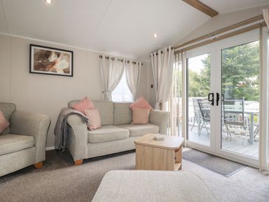 A living room with sofas coffee table and glass doors opening to a balcony at Pams Place in Crantock