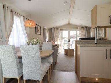 A living and dining area with a dining table and chairs a sofa a coffee table and sliding glass doors at Pams Place in Crantock