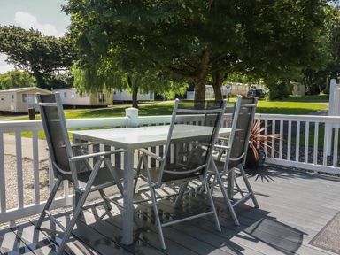 An outdoor patio with a table and four chairs surrounded by white railing at Pams Place in Crantock