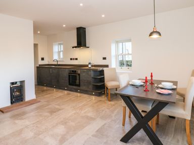 A kitchen with dark cabinets and a dining table set with plates and red candles at Luham Cottage in Edenhall near Langwathby