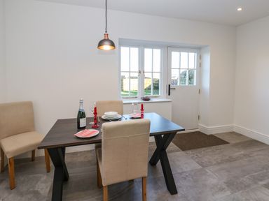 A dining area with a table set for two near a window and door at Luham Cottage Edenhall near Langwathby