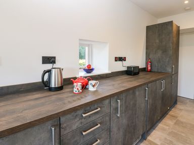 A kitchen countertop with a kettle teapot mugs toaster and fruit bowl at Luham Cottage Edenhall near Langwathby