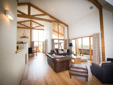 A living room with leather sofas wooden beams and large windows at Aurae in Cawdor near Inverness