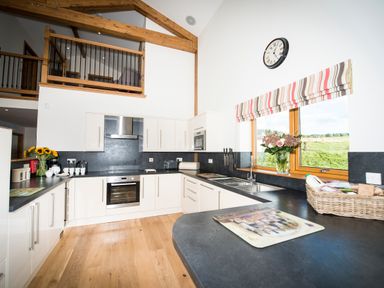 A kitchen with white cabinets black countertops wooden floor and flowers on the counter at Aurae in Cawdor near Inverness