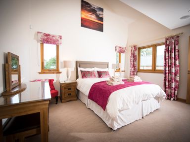 A bedroom with a double bed bedside tables lamps and a dressing table at Aurae Cawdor near Inverness