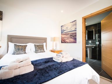 A bedroom with a bed towels on a blanket and an open door leading to a bathroom at Aurae in Cawdor near Inverness