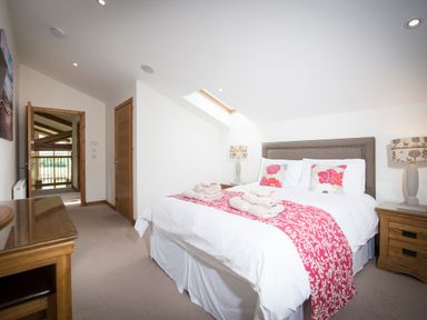 A bedroom with a double bed towels bedside tables lamps and a desk at Aurae in Cawdor near Inverness