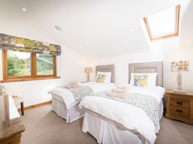 A bedroom with two single beds each with a pillow and folded towels a window and skylight at Aurae in Cawdor near Inverness