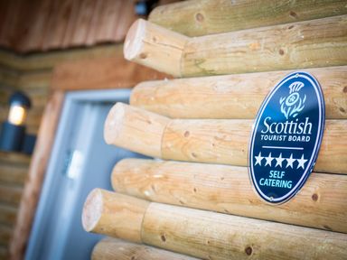A wooden log exterior wall with a Scottish Tourist Board five star self catering sign at Aurae in Cawdor near Inverness
