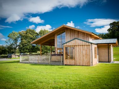 A wooden house with large windows and a fenced porch on a grassy lawn at Atlas in Cawdor near Inverness