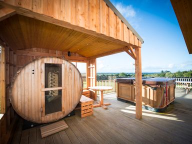 A wooden sauna, a round table with benches, and a covered hot tub on a wooden deck at Atlas in Cawdor near Inverness