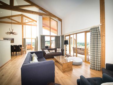 A living room with sofas a wooden coffee table and large windows with curtains at Atlas in Cawdor near Inverness