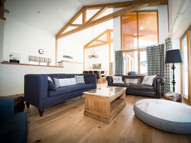 A living room with sofas a wooden coffee table a large window and exposed wooden beams at Atlas in Cawdor near Inverness