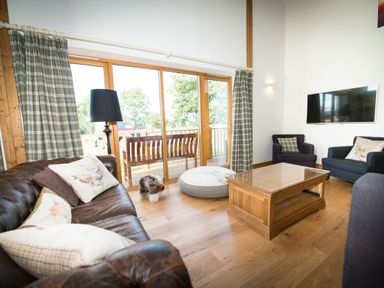 A living room with leather and fabric sofas a wooden coffee table and a floor lamp near glass doors at Atlas in Cawdor near Inverness