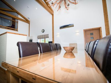 A dining room with a long wooden table and chairs beneath wooden ceiling beams at Atlas in Cawdor near Inverness